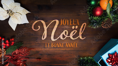 “Joyeux Noel et Bonne Annee” t.i. Merry Christmas and Happy New Year in French language on a wooden background with decoration vertical view for smartphone digital wishes messages. 16:9 size. photo