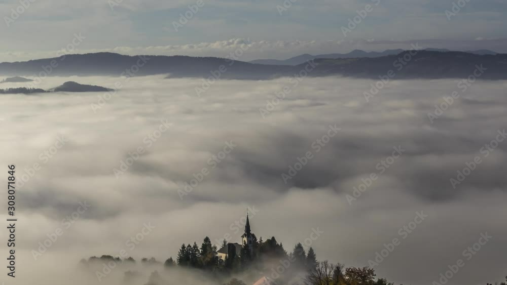 Time lapse low altitude fog cover valley with visible village and church Time lapse low altitude fog cover valley with visible village and church
