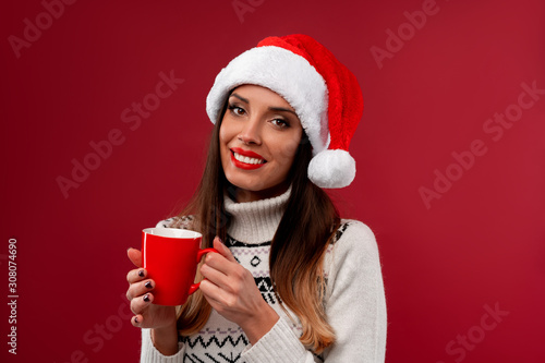 Close up portrait beautifiul caucasian woman in red Santa hat on red studio background. Christmas and New Year holiday concept.
