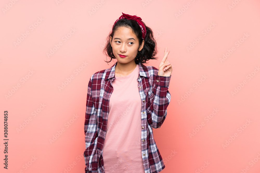 Asian young woman over isolated pink background with fingers crossing and wishing the best Asian young woman over isolated pink background with fingers crossing and wishing the best