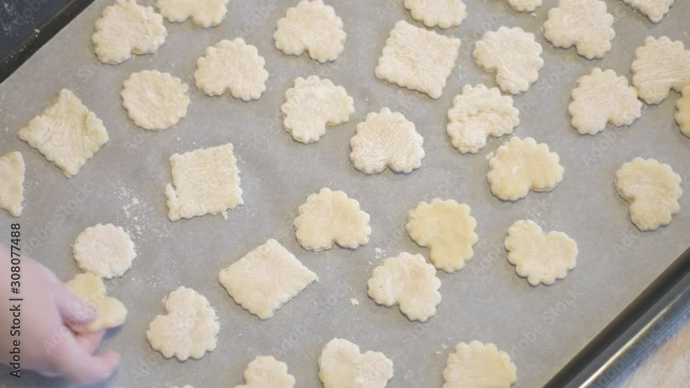 Little daughter helps mom in the kitchen with baking. Cut the cookies with cookie cutters. Spread cookie blanks on baking paper. Little daughter helps mom in the kitchen with baking. Cut the cookies with cookie cutters. Spread cookie blanks on baking paper.