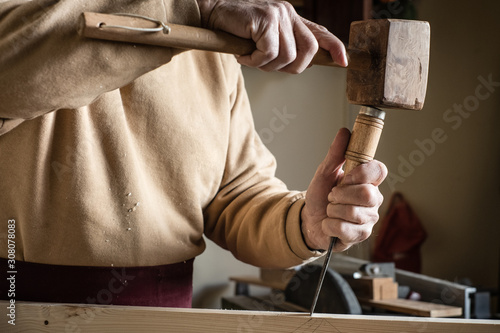 Carpenter working with a wooden hammer and a gouge photo