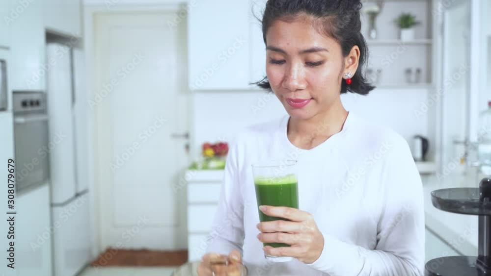 Woman pouring juice into a glass while drinking Woman pouring juice into a glass while drinking