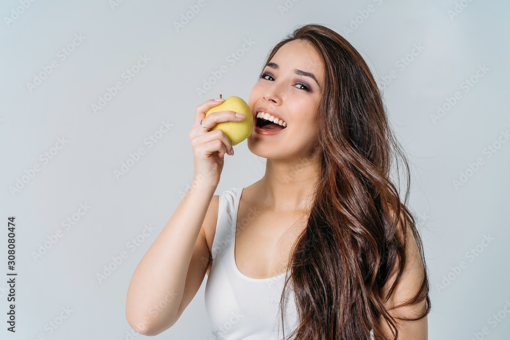 Beauty portrait of smiling young asian woman girl holding green apple near clean face on grey background Beauty portrait of smiling young asian woman girl holding green apple near clean face on grey background