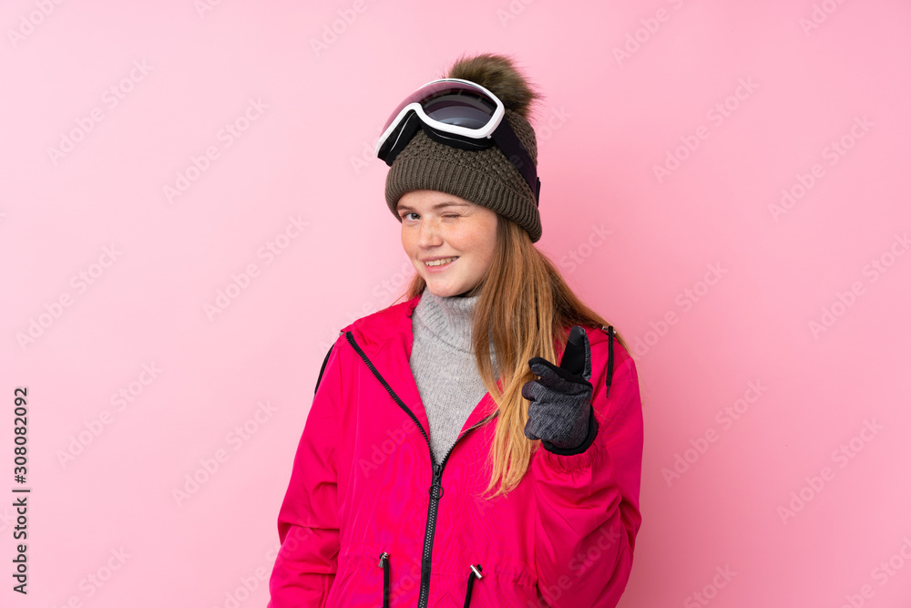 Ukrainian teenager skier girl with snowboarding glasses over isolated pink background points finger at you Ukrainian teenager skier girl with snowboarding glasses over isolated pink background points finger at you