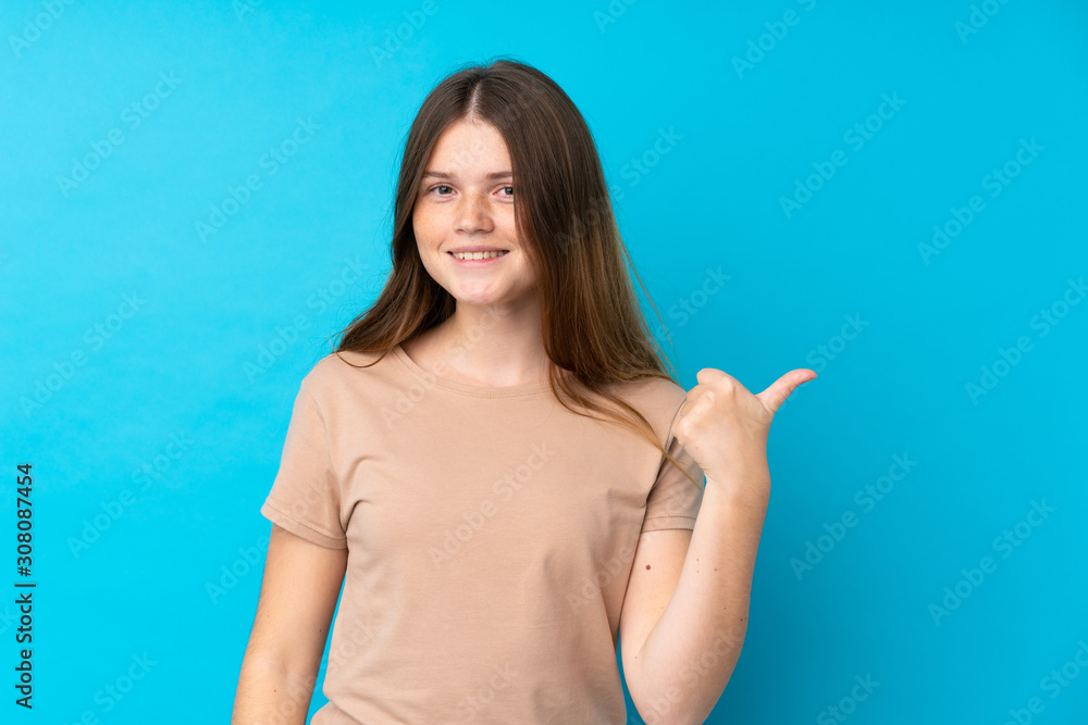Ukrainian teenager girl over isolated blue background pointing to the side to present a product Ukrainian teenager girl over isolated blue background pointing to the side to present a product