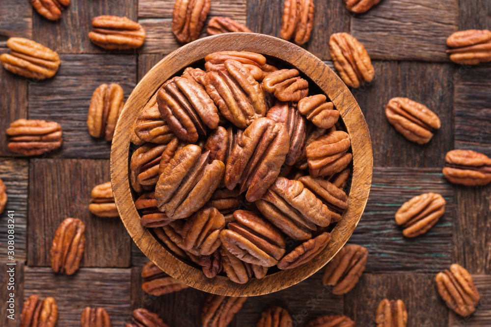 pecan nuts peeled in wooden bowl, top view. - obrazy, fototapety, plakaty 
