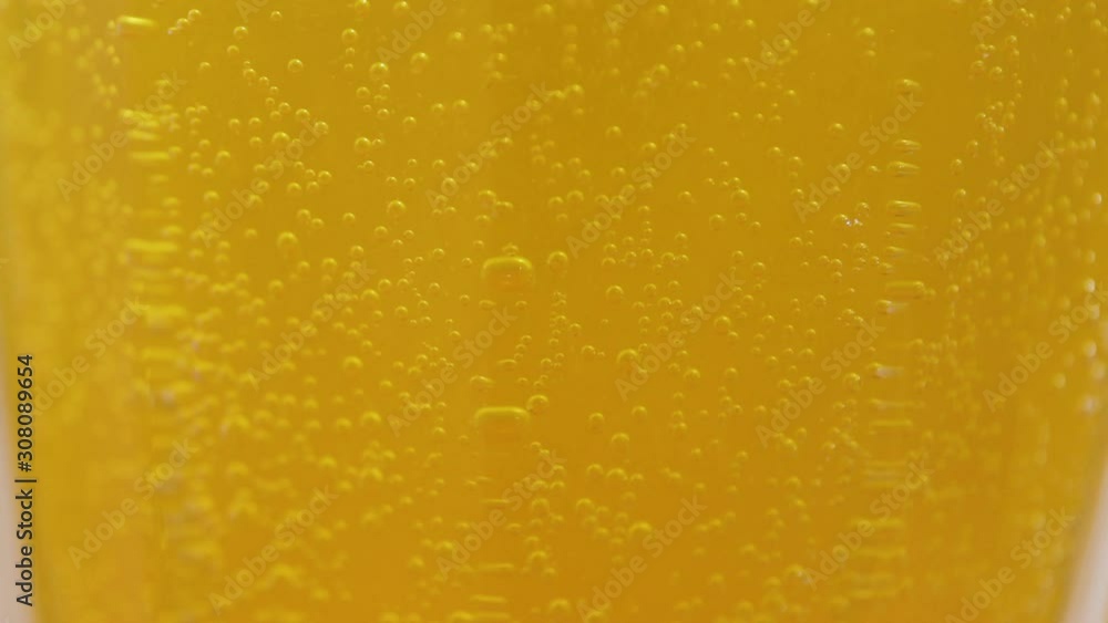 Yellow carbonated drink with vitamin C closeup shot. Round bubbles play in a glass and rise up. Cold drink to treat colds. Yellow carbonated drink with vitamin C closeup shot. Round bubbles play in a glass and rise up. Cold drink to treat colds.