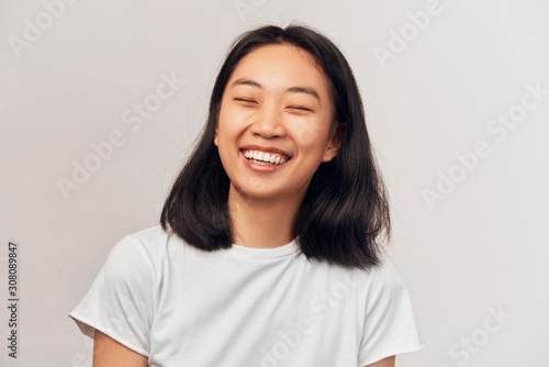 Fotografie Positive cheerful female closing eyes tight cannot stop laughing at good joke