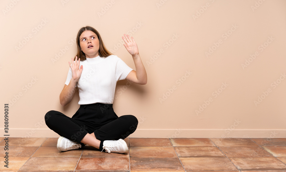 Ukrainian teenager girl sitting on the floor nervous and scared Ukrainian teenager girl sitting on the floor nervous and scared