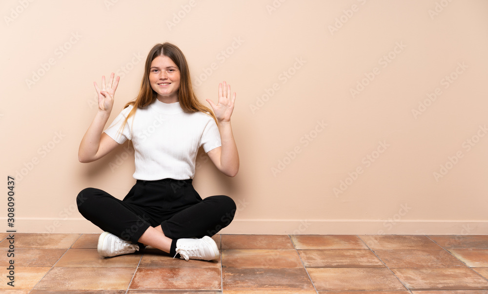 Ukrainian teenager girl sitting on the floor counting nine with fingers Ukrainian teenager girl sitting on the floor counting nine with fingers