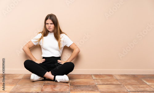 Ukrainian teenager girl sitting on the floor angry