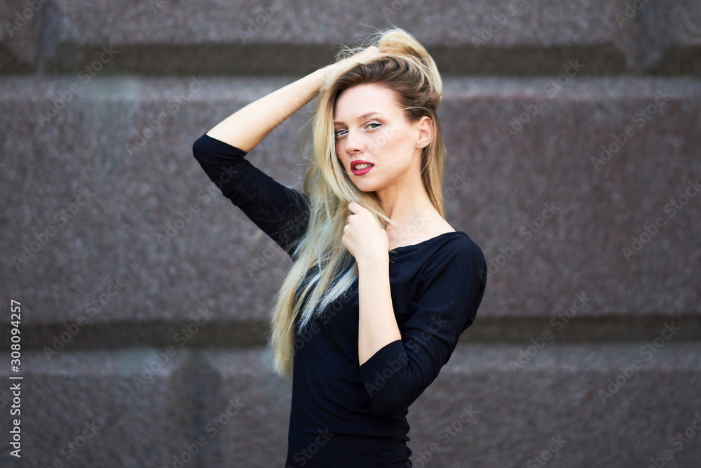 Attractive blonde in a black dress. Against the background of a stone wall. Attractive blonde in a black dress. Against the background of a stone wall.