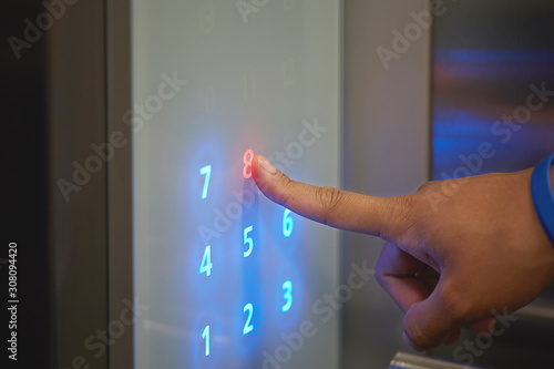 Man or woman pressing digital numbers. Blue Arabic numbers in lift passenger interior. Close up and selective.