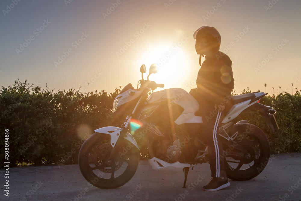Fototapeta premium Asian woman with helmet and wearing and fasten before riding big bike motorcycle on the road for safety