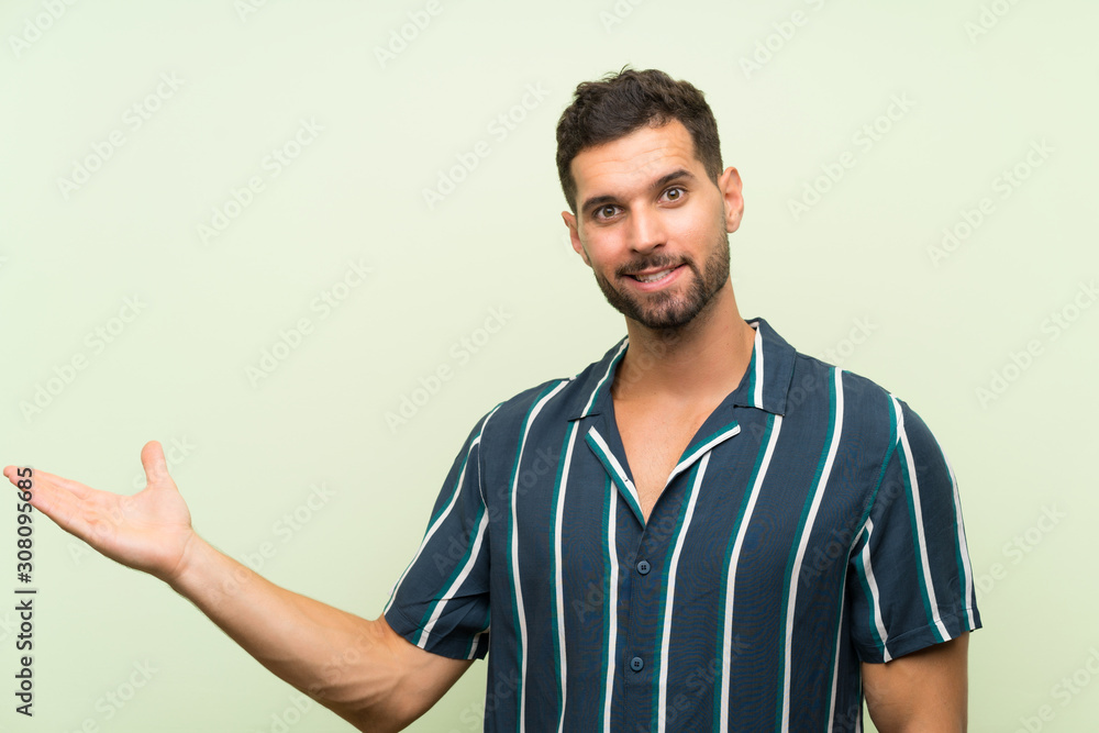 Handsome man over isolated background holding copyspace imaginary on the palm Handsome man over isolated background holding copyspace imaginary on the palm
