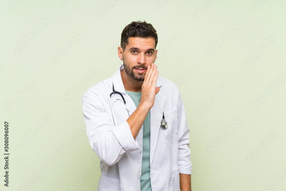 Young doctor man over isolated green wall whispering something Young doctor man over isolated green wall whispering something