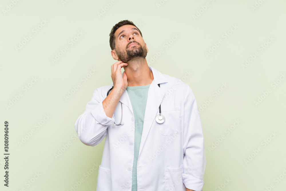 Young doctor man over isolated green wall thinking an idea Young doctor man over isolated green wall thinking an idea