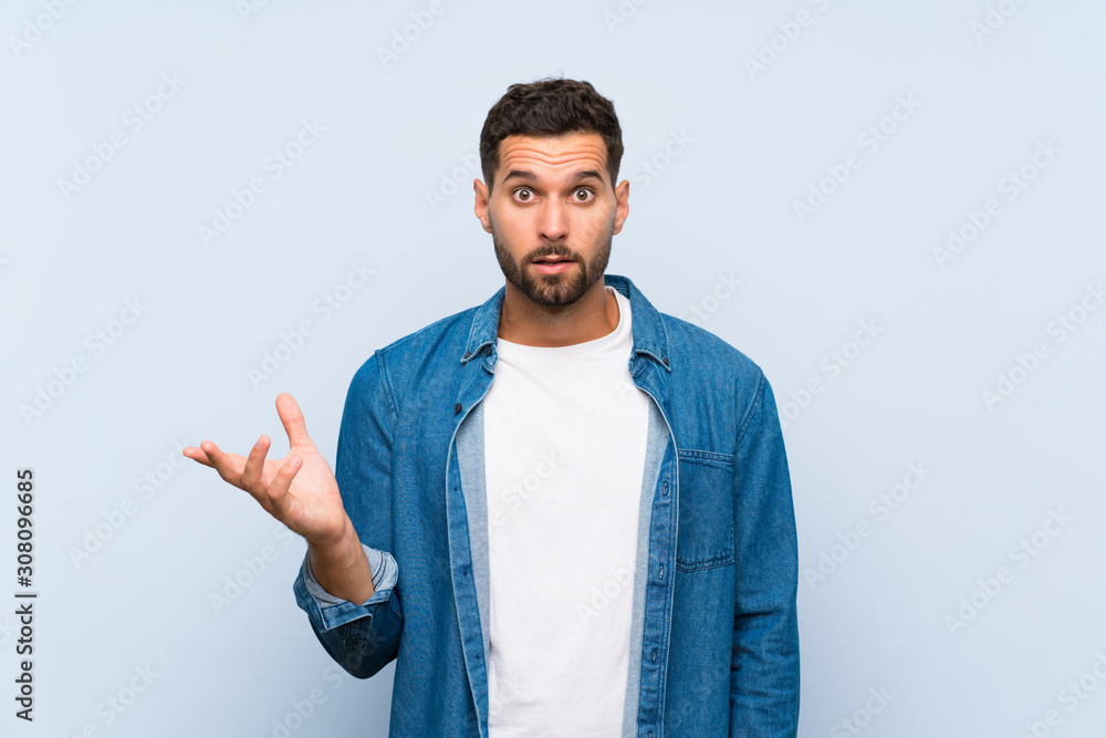 Handsome man over isolated blue background making doubts gesture Handsome man over isolated blue background making doubts gesture