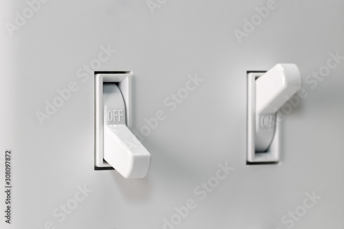 Closeup of white duplex light switch turned off and another turned on in background. Concept of energy saving, conservation