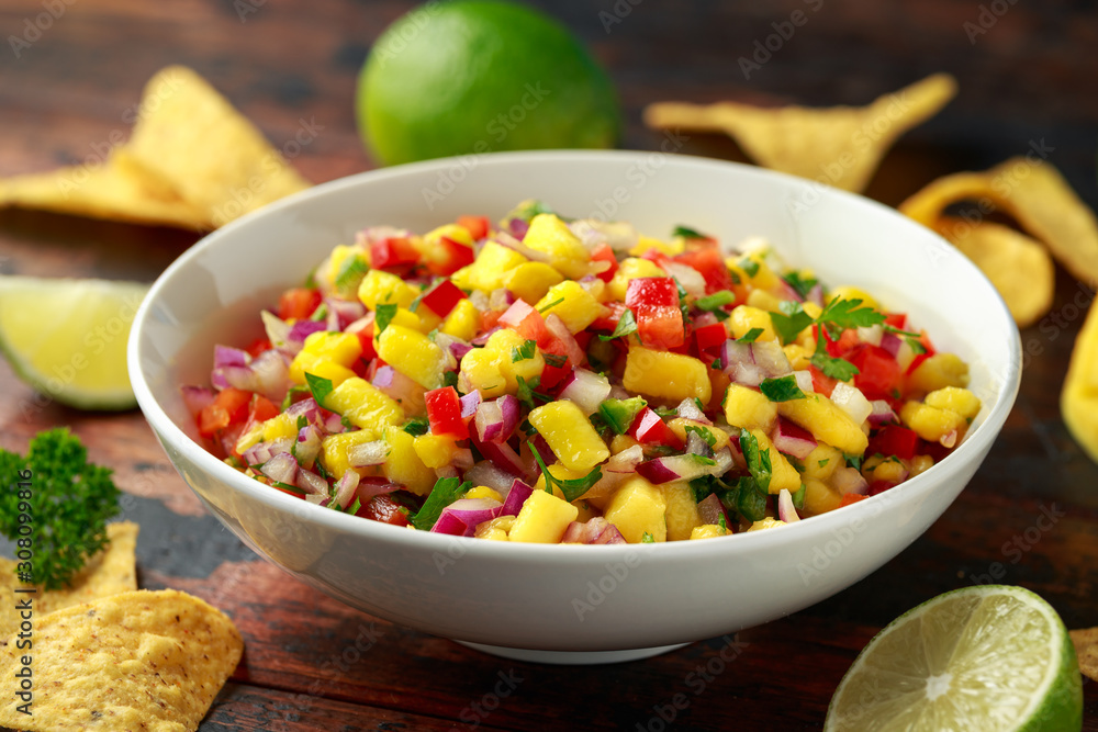 Bowl of fresh Mango Salsa with nachos chips and herbs. Healthy Vegan, Vegetables food. Bowl of fresh Mango Salsa with nachos chips and herbs. Healthy Vegan, Vegetables food.