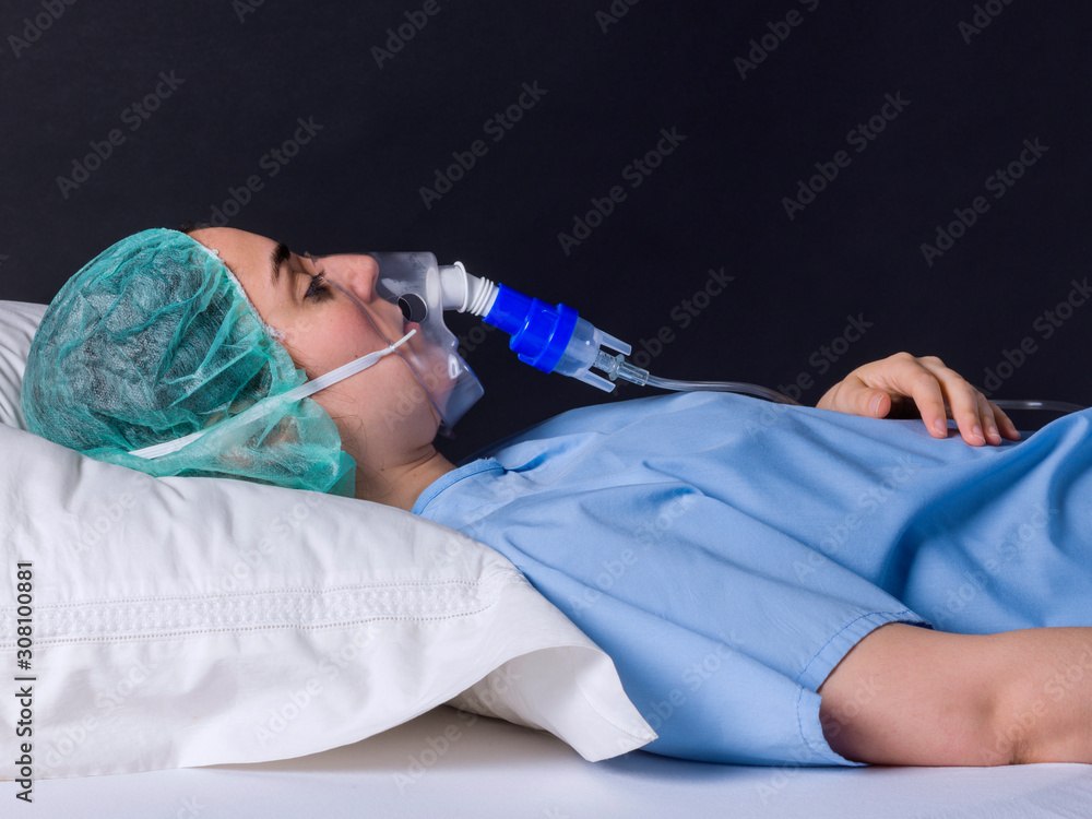 Teenage girl lying in a hospital bed with oxygen mask