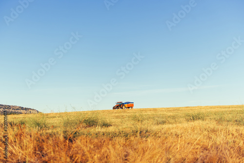 Red agricultural tractor with truck stands on planting field.