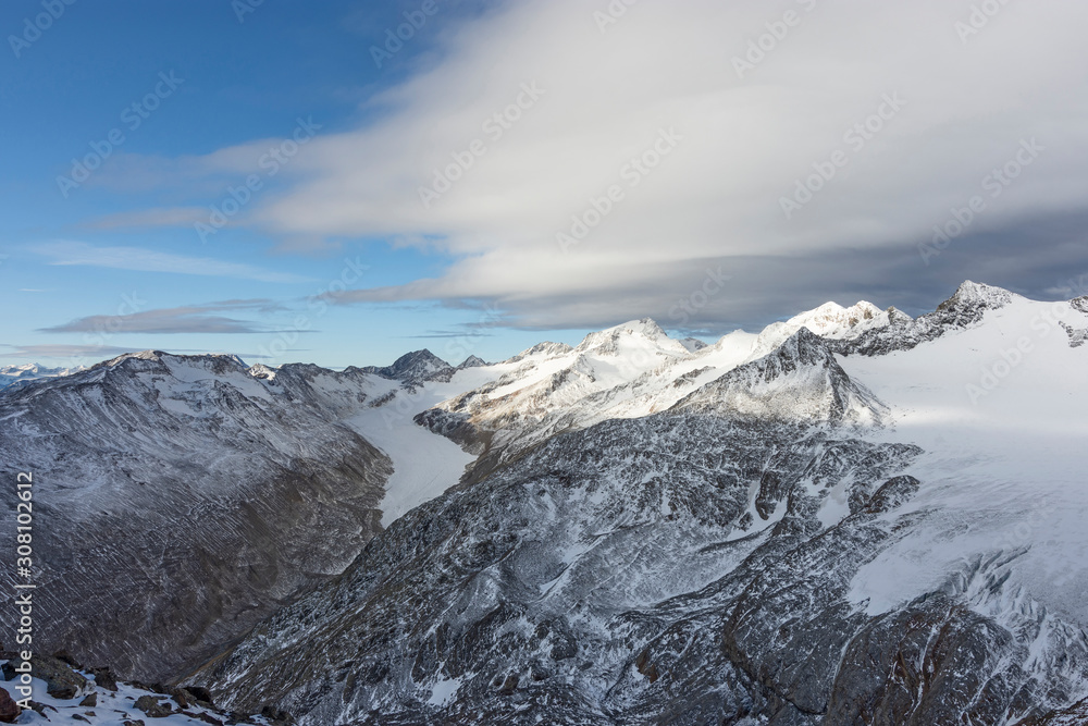 Dramatic cloudscape over snow-covered glacier landscape with rocky mountains. Oetztal Alps, Tirol, Austria