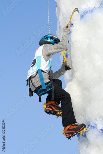 A young female iceclimber climbs up the mountain photo