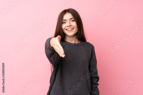 Young woman over isolated pink background shaking hands for closing a good deal