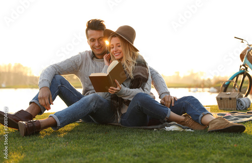 Happy young couple reading book while having picnic outdoors