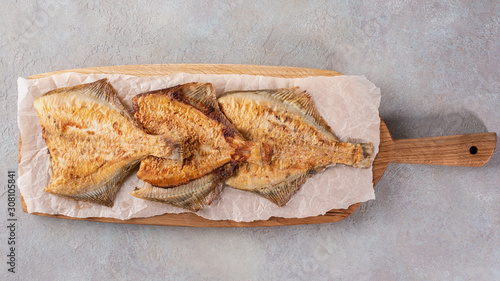 Grilled flounder on a serving oak board on a light background. Flat lay.