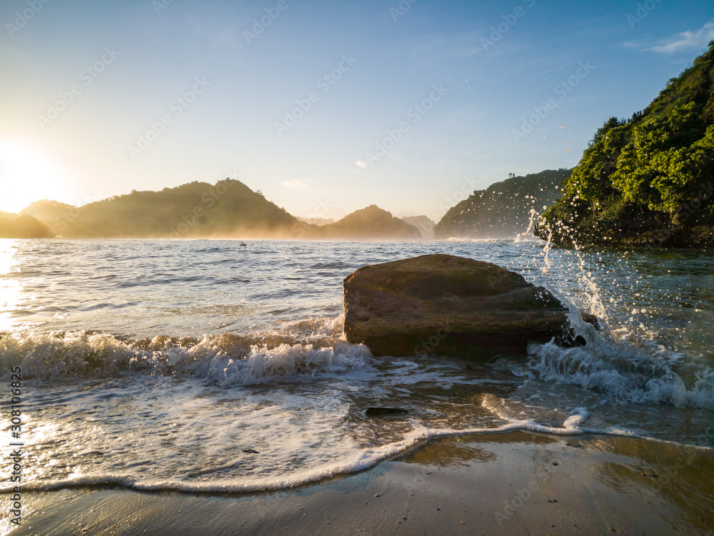 Obraz premium Wonderful view rock hit by weaves on beach in the morning