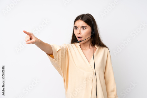 Young telemarketer woman over isolated white background pointing away