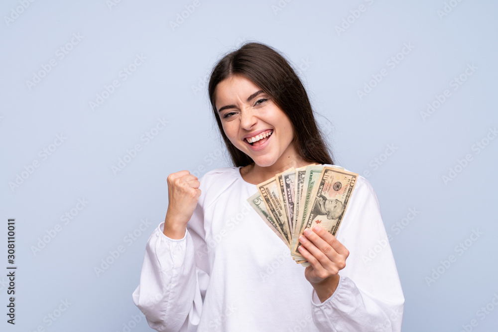 Young woman over isolated blue background taking a lot of money Young woman over isolated blue background taking a lot of money