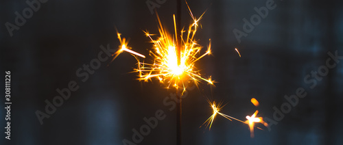 Sparklers for Christmas and New Year close-up in the form of a banner and on a blue background