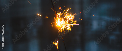 Sparklers for Christmas and New Year close-up in the form of a banner and on a blue background