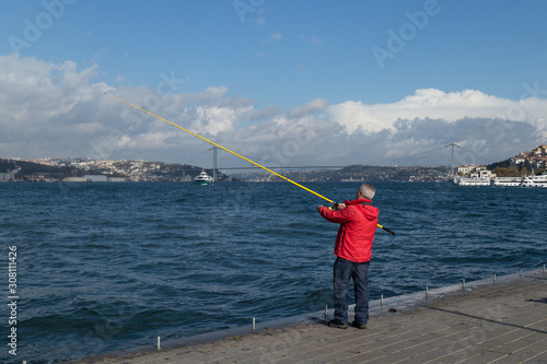 The man is fishing on the Bosphorus from Istanbul.