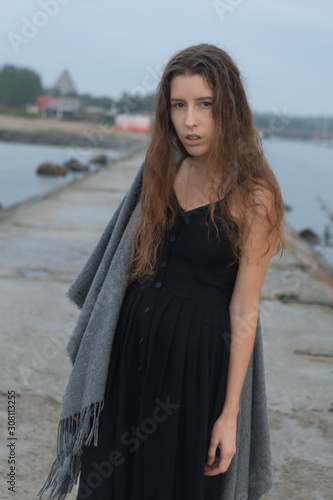 A beautiful and sad girl stands on a stone pier with a landscape on the sea. it rains © Underwater girls