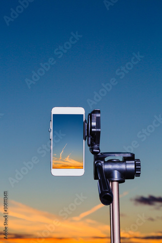 Smartphone on tripod capturing image of sundown in vertical mode
