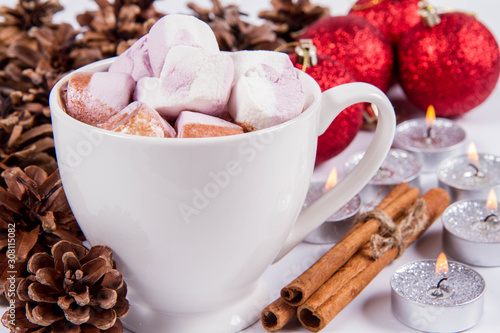 Cup of hot chocolate with marshmallows    some cinnamon sticks  cones  christmas balls and candles