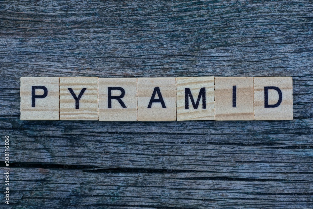 Fototapeta premium word pyramid made from gray wooden letters lies on a gray table