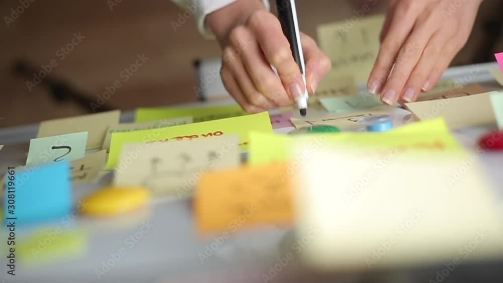 Business woman writes notes using post stickers on paper. Brainstorming, teamwork. Business woman writes notes using post stickers on paper. Brainstorming, teamwork.