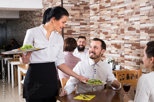 Smiling waitress serving meal for restaurant guests photo