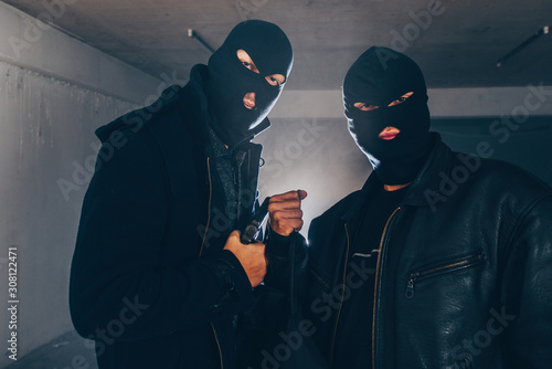 Foto Thiefs with masks holding gun in dark room