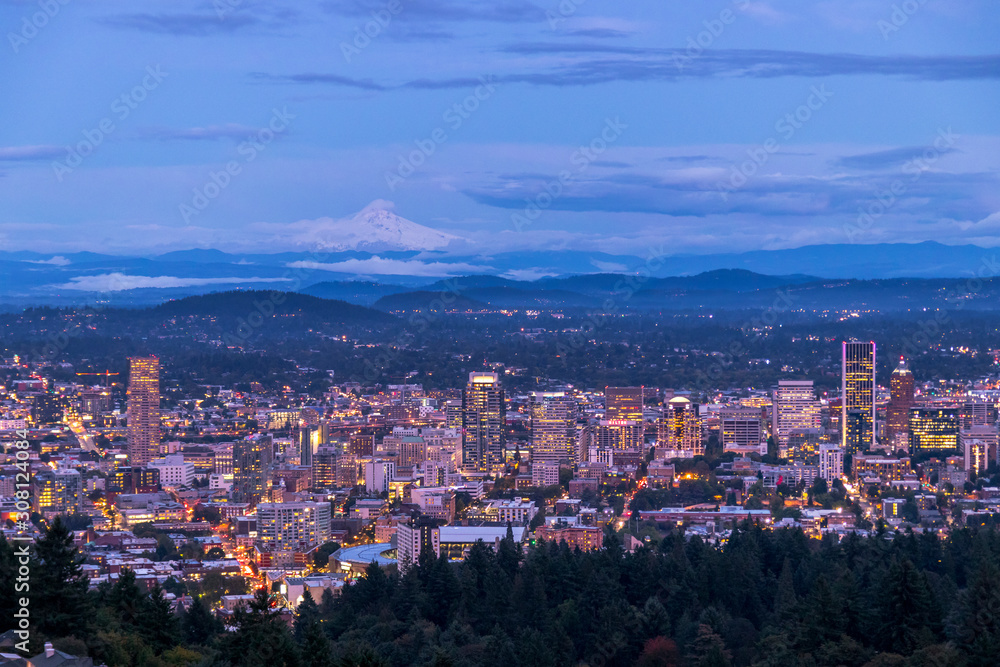 Portland Oregon cityscape skyline transitioning from day to night and Mt. Hood in the far distance. Night coming over the city of Portland Oregon USA America. Urban city lifestyle.