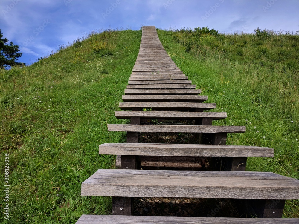 Stairway on a grassy hill, leading up into the sky 