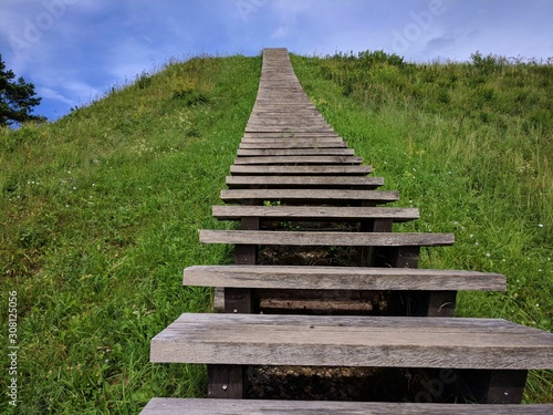 Stairway on a grassy hill  leading up into the sky 
