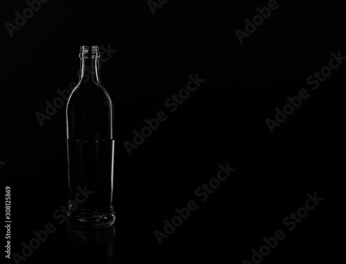 Silhouette of a glass bottle on a black background . Empty space for your lettering. © Pavel Kovalevsky