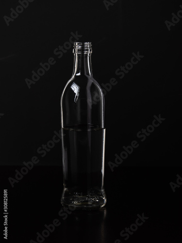 Silhouette of a glass bottle on a black background . Empty space for your lettering.